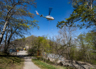 Hubschrauber im Wald. Der Hubschrauber überfliegt das gesamte Gebiet und fliegt die Bäume und Wiesen ab. Er ist für Fußgänger vom Boden aus deutlich zu sehen. Wahrscheinlich im Einsatz.