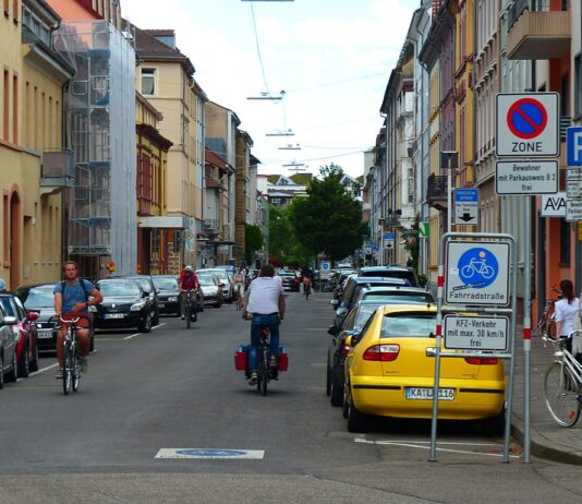 Mehrere Fahrradfahrer fahren mitten auf der Sophienstraße in Karlsruhe. Zu beiden Seiten sind eine Menge Autos geparkt. Ein Schild an der Seite sowie eines, das auf die Straße aufgemalt ist, weist darauf hin, dass es sich um eine Fahrradstraße handelt.