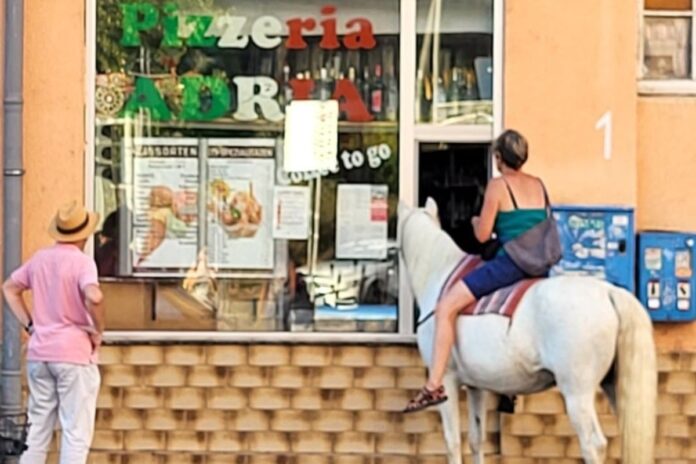 Frau mit Pferd an Eisdiele