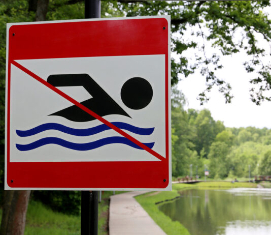 Schwimmverbot im Baggersee. Das Schild steht an einem Badesee und verweist auf das Verbot, das Gewässer zu betreten. Die Ursache dafür kann eine besondere Gefährdungslage sein.