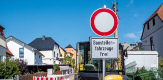 Baustelle mit Schild. Diese Straße ist wegen einer Baustelle für den normalen Verkehr gesperrt. Nur Baufahrzeuge dürfen passieren. Das schränkt den Verkehr ein.