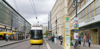 Bahn an Haltestelle mit Reisenden