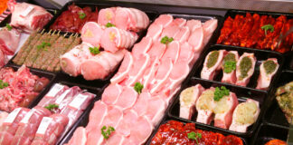 An der Kühltheke in einem Supermarkt gibt es eine große Auswahl verschiedener Fleischprodukte. Das Fleisch liegt für Verbraucher sichtbar und schön angeordnet in der Theke. Beim Einkaufen können Kunden sich frisches Fleisch zum Kochen oder Grillen mitnehmen.