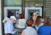 Menschen stehen Schlange, um Geld abzuheben: Zahlreiche Kunden stehen vor Geldautomaten, um mit ihrer EC-Karte Bargeld - Geldscheine - von ihrem Girokonto abzuheben.