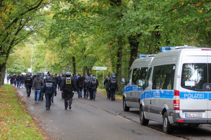 Abgegrenzter Wald mit vielen Beamten. Die Polizisten gehen in voller Montur durch ein Waldstück. Mehrere bewaffnete Polizeibeamte einer Einheit.