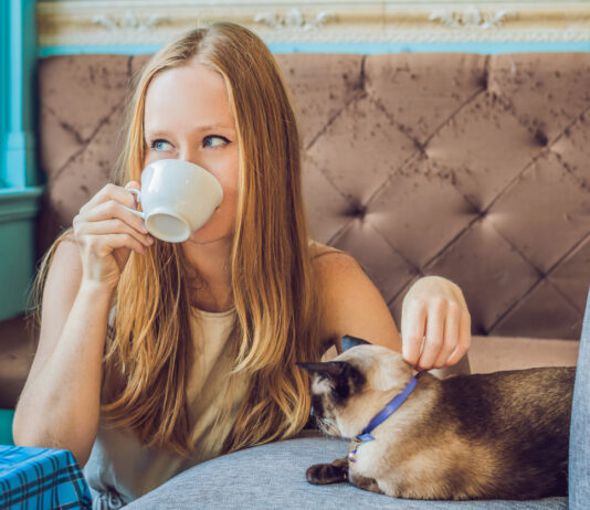 Eine Frau trinkt im Katzencafé einen Kaffee.