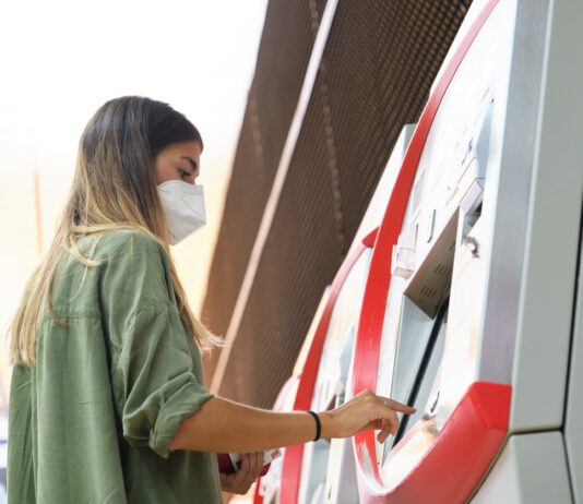 Eine Frau kauft ein Bahnticket am Automaten.