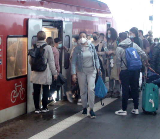 Bahnreisende mit Maske.