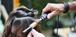 Friseur mit Lockenstab an einer Kundin.