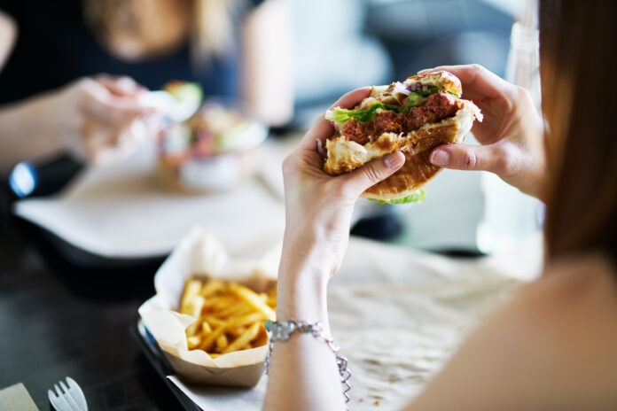 Eine Frau isst einen Burger im Restaurant.