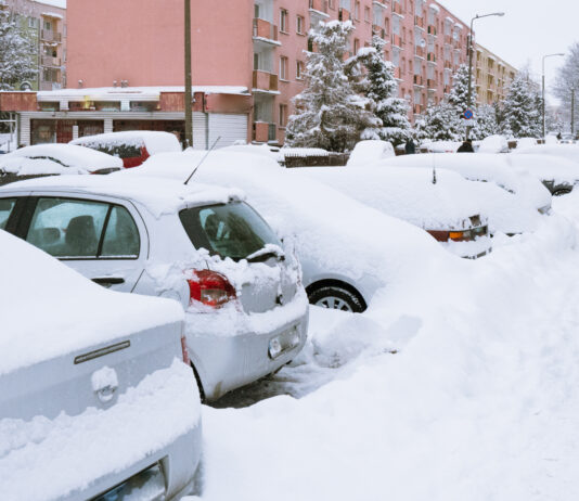 Parkende Autos sind vom Schnee bedeckt.