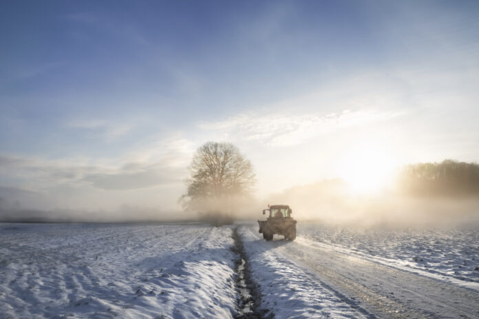 Ein Traktor fährt auf einer verschneiten Straße.