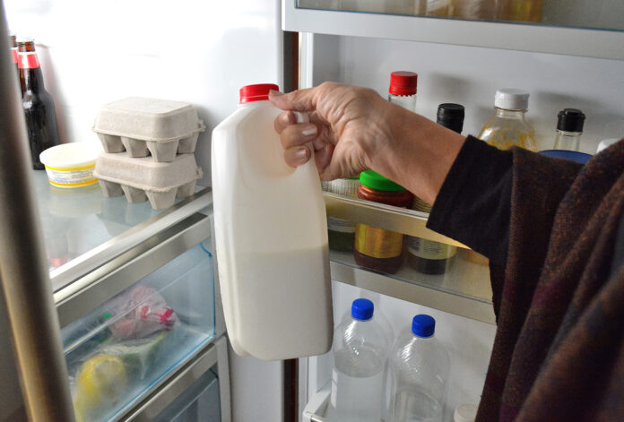 Eine Frau nimmt eine Flasche Milch aus dem Kühlschrank.