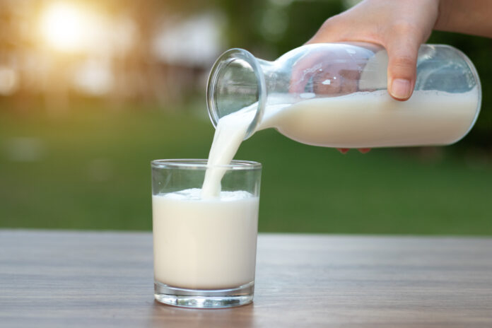 Milch wird in ein Glas gegossen.
