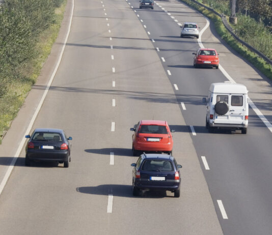 Verschiedene Autos fahren auf einer deutschen dreispurigen Autobahn mit mittlerer Grünfläche