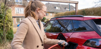 Eine junge Frau lädt ihr Elektroauto an einer Ladestation auf