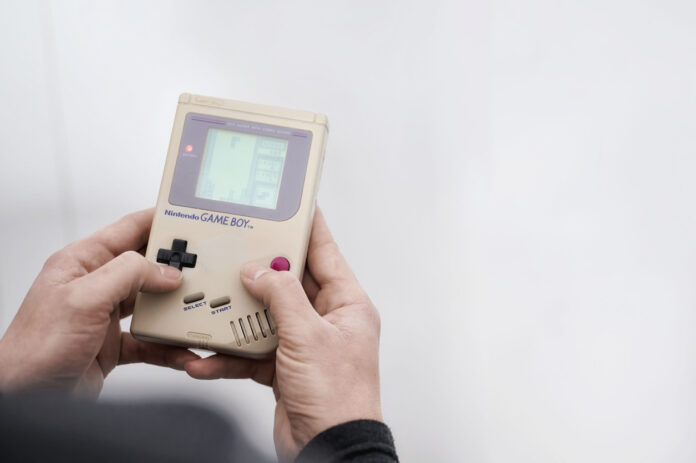 Ein Mann hält einen Gameboy in der Hand