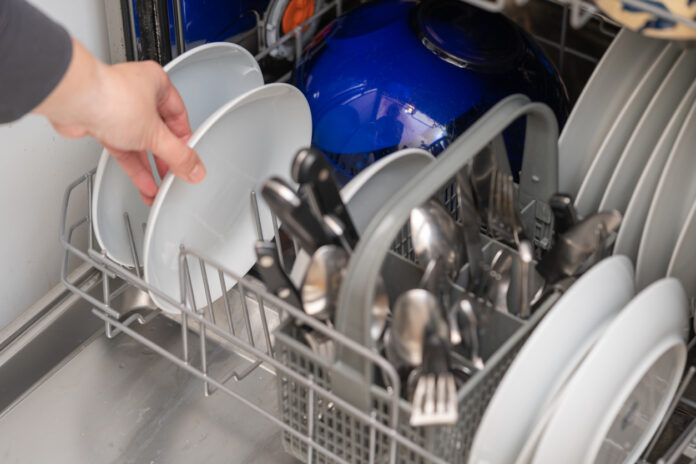 Frau benutzt Geschirrspüler für Hausarbeit