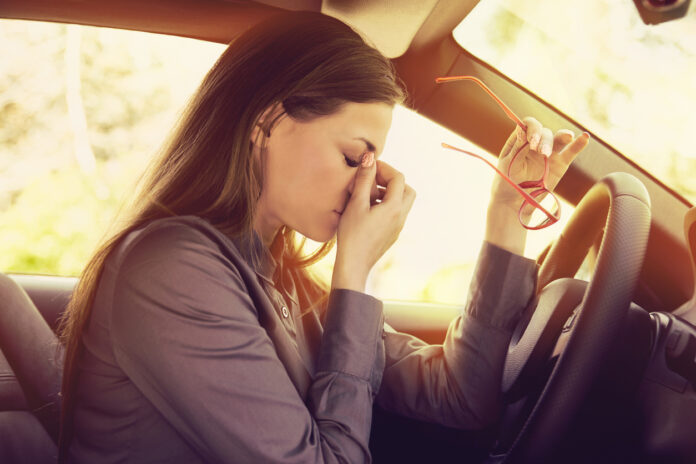 Eine Fahrerin im Auto ist krank und fühlt sich unwohl.