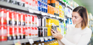 Eine Frau steht im Supermarkt und hält ein Getränk in der Hand