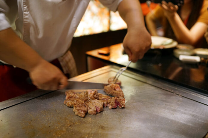 Eine Person zerkleinert Fleisch auf einer Grillplatte