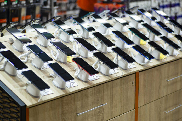 Viele Smartphones liegen zum Verkauf bereit in einem Geschäft nebeneinander aufgereiht.
