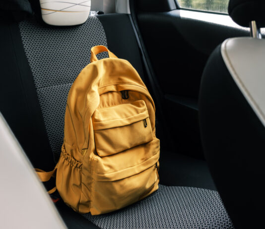 Ein gelber Rucksack liegt auf der Rückbank eines Autos.