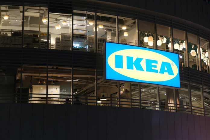 Ikea Möbelhaus Ansicht von vorn bei Nacht. Die gläserne Front des Möbelhauses im Dunkeln. Das große Ikea Schild leuchtet. Vorn befindet sich auch der Eingang in das schwedische Shoppingcenter.
