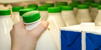 Eine Hand greift nach Milch im Supermarkt.