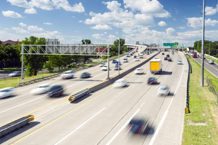 Mehrspurige Autobahn mit fahrenden Fahrzeugen bei mäßigem Verkehr.