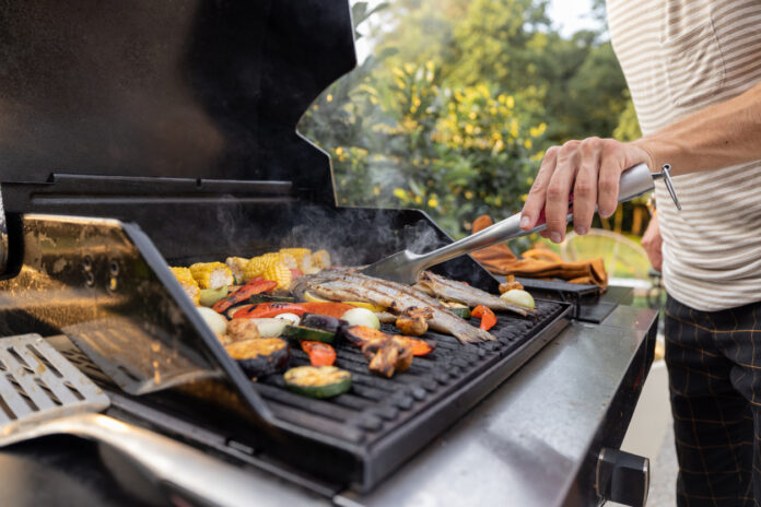 Ein gut beladener Grill mit Gemüse und Fisch.