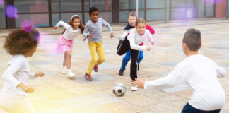 Jungen und Mädchen spielen gemeinsam auf dem Schulhof Fußball