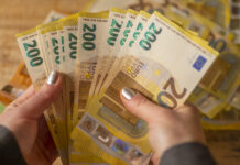 Weibliche Hände mit Nagellack halten etliche 200-Euro-Scheine zum Zählen. Dahinter liegt noch mehr Geld. Verschwommen erkennt man noch mehr 200-Euro-Scheine sowie einen 50-Euro-Schein.