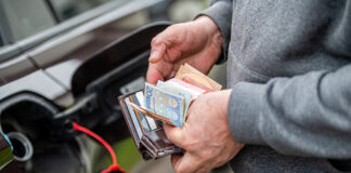 Ein Mann zählt die Geldscheine in seinem Portemonnaie – er sucht sich das Geld zusammen, um die Tankfüllung an der Tankstelle zu bezahlen.