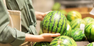 Eine Kundin wählt in der Obstabteilung eines Supermarktes eine Wassermelone aus.