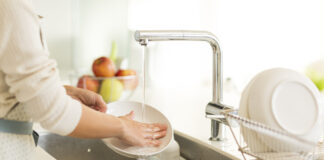 Eine Frau wäscht das Geschirr in einem Spülbecken zu Hause ab