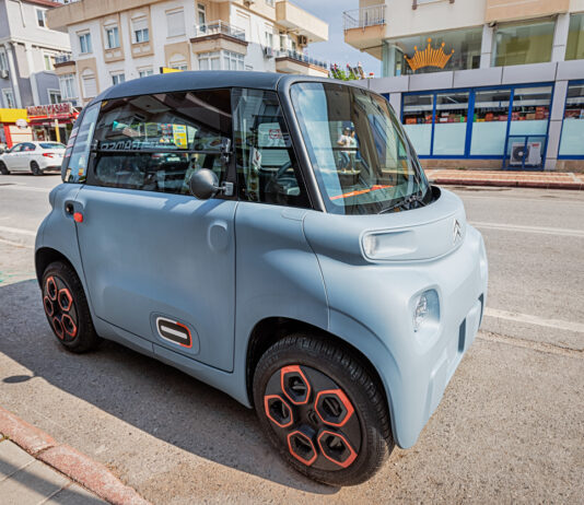 Ein Mini E-Auto parkt am Gehsteig.