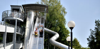 Opa und Enkelin rutschen eine Riesen-Rutsche runter in einem XXL-Park.