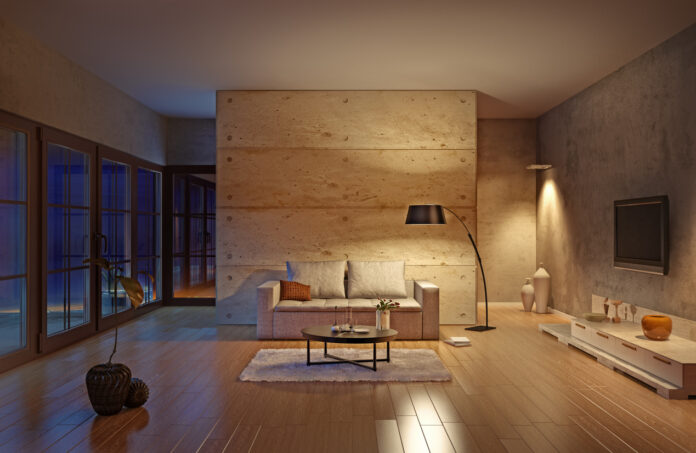 Ein sehr modern eingerichtetes Wohnzimmer in Beige mit Fernseher, Sofa, Lampe, Tisch und anderen Möbeln. Das Zimmer hat eine modern helle Farbe.