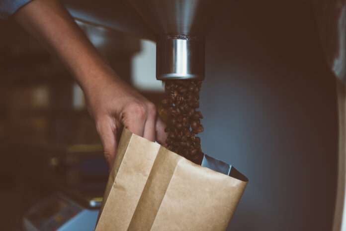 Befüllen einer Papiertüte mit Kaffeebohnen