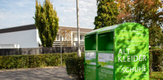 Ein grüner Kleidercontainer steht an einem Weg.