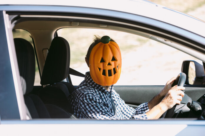 Mann mit Maske am Steuer eines Autos