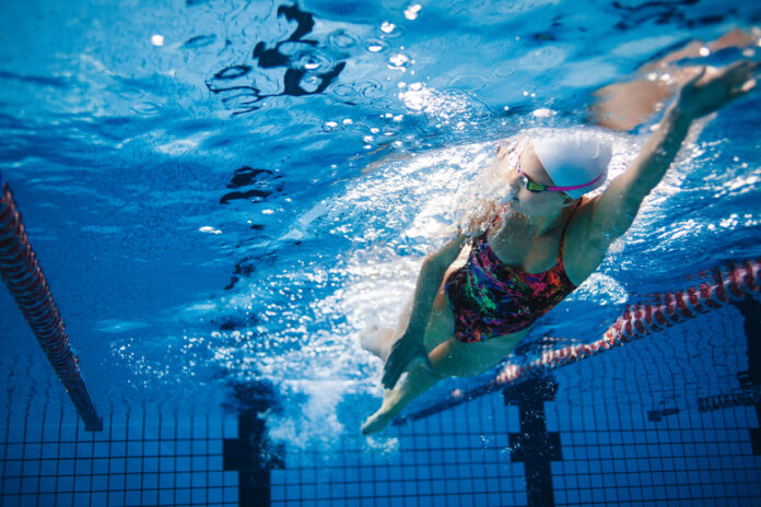 Eine Frau schwimmt unter Wasser in einem Schwimmbad