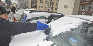 Ein Auto wird vom Schnee befreit.