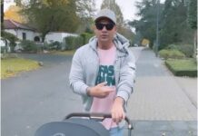 Der prominente Sänger Pietro Lombardi trägt ein rosa Shirt, Sonnenbrille und Kappe. Dabei läuft er über die Straße und S schiebt den Kinderwagen mit seinem Kind durch die Stadt.