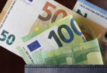 Mehrere Euroscheine gucken aus einer Geldbörse heraus. Darunter befinden sich mindestens zwei 100-Euroscheine, ein 50-Euroschein, und im Hintergrund ein 20-Euroschein. Das Portemonnaie ist mit Bargeld gut gefüllt.