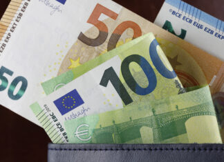 Mehrere Euroscheine gucken aus einer Geldbörse heraus. Darunter befinden sich mindestens zwei 100-Euroscheine, ein 50-Euroschein, und im Hintergrund ein 20-Euroschein. Das Portemonnaie ist mit Bargeld gut gefüllt.