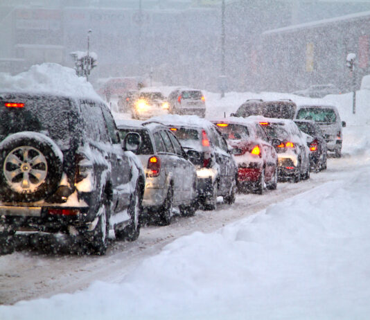 Viele Autos stehen im Stau auf einer zugeschneiten Straße. Eine Frostpeitsche trifft auf Deutschland.