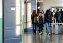 Schüler auf dem Weg zum Unterricht in einem Schulgebäude. Die Kinder und Jugendlichen gehen mit ihren Rucksäcken und Schultaschen auf dem Rücken in das Klassenzimmer.