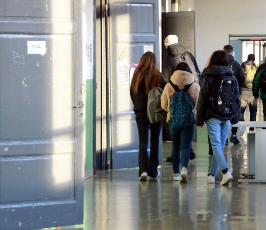 Schüler auf dem Weg zum Unterricht in einem Schulgebäude. Die Kinder und Jugendlichen gehen mit ihren Rucksäcken und Schultaschen auf dem Rücken in das Klassenzimmer.